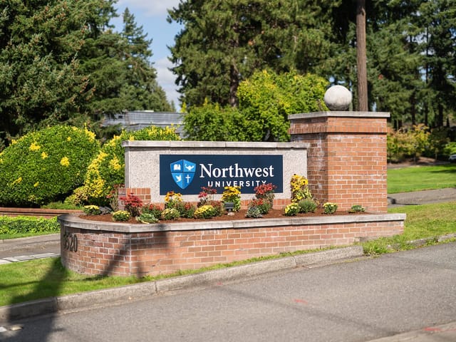 The Northwest University sign at the Kirkland campus entrance, framed by spring flowers