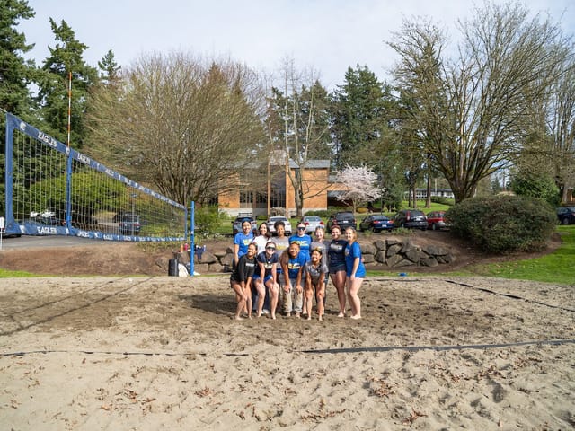 Volleyball players gathered on the campus sand court