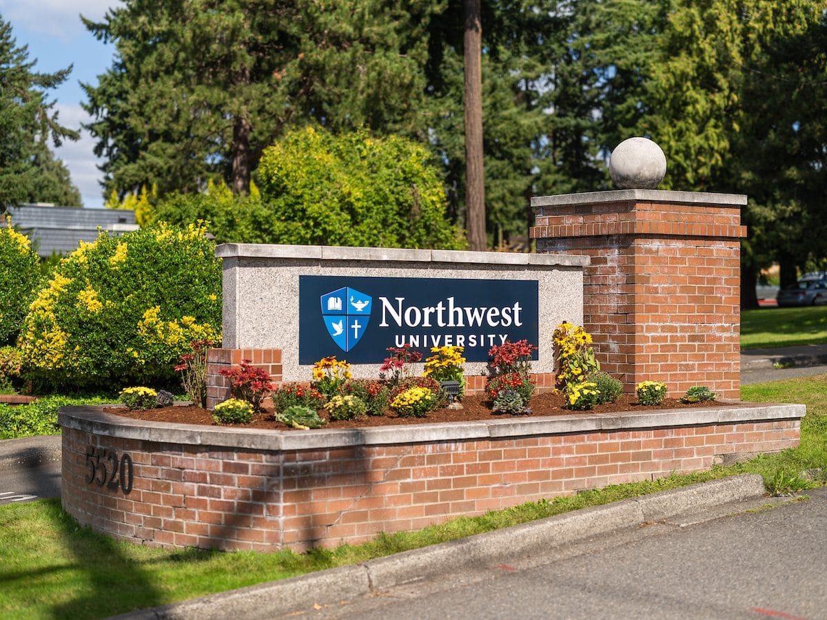 The Northwest University entrance sign in Kirkland, framed by spring flowers