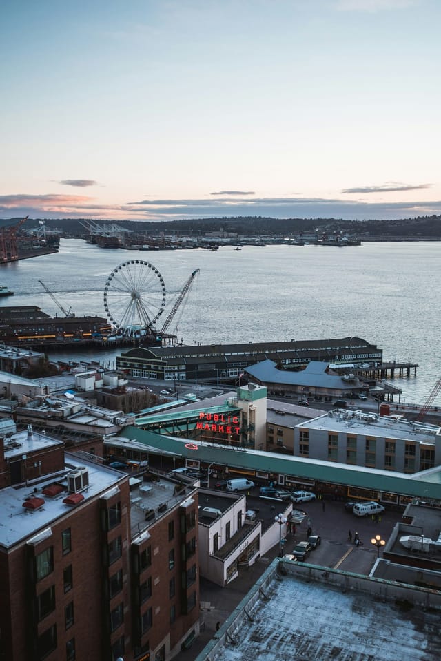 Pike Place Market’s Public Market sign and the Seattle Great Wheel on Elliott Bay at dusk