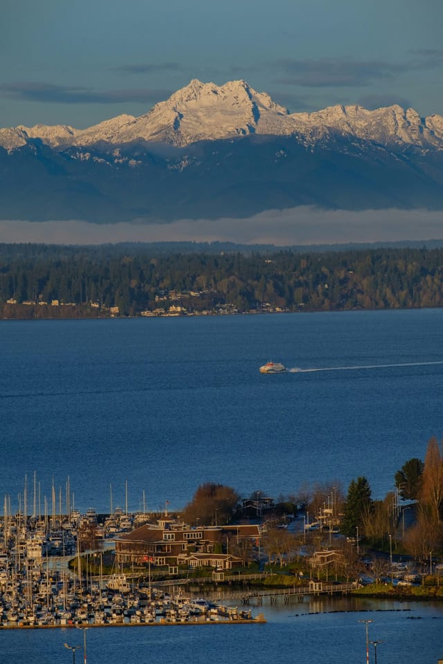 Snow-capped mountains rising beyond Puget Sound, with a marina in the foreground